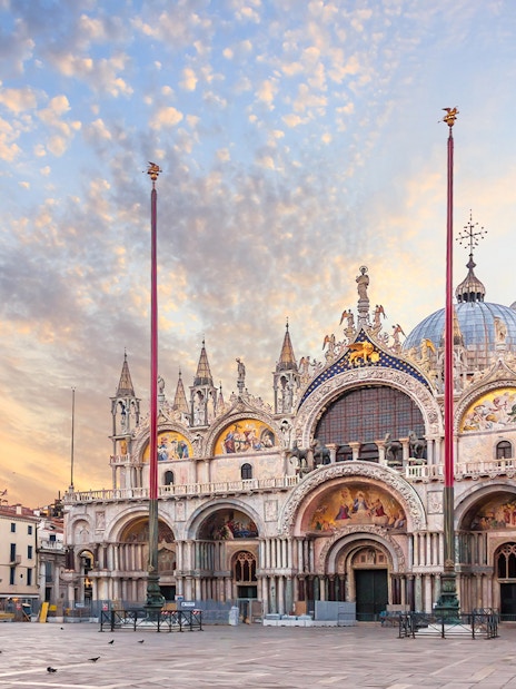 St. Mark's Basilica exterior in Venice with ornate facade and domes at sunset.