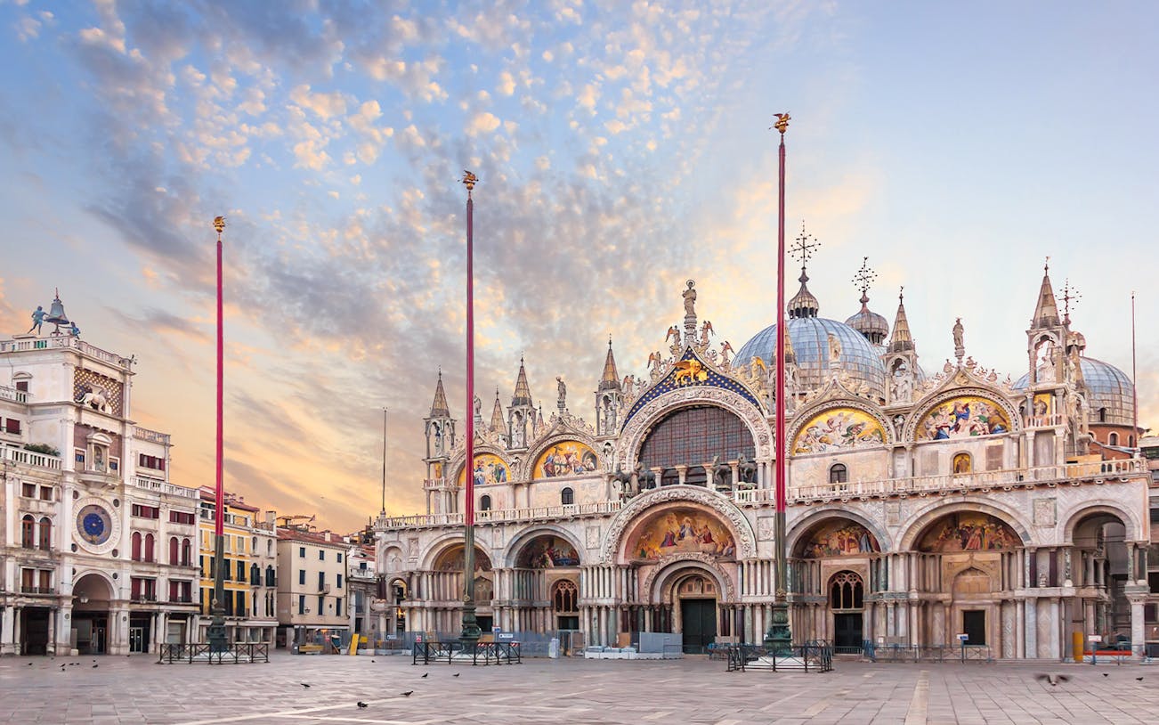 St. Mark's Basilica exterior in Venice with ornate facade and domes at sunset.