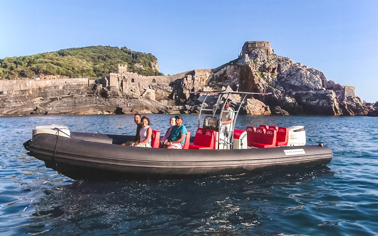 Tourists on a private boat tour near rocky coastline in Cinque Terre.