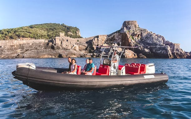 Tourists on a private boat tour near rocky coastline in Cinque Terre.