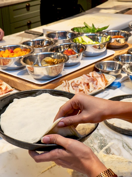 Preparing pizza dough with toppings in a Rome cooking class.