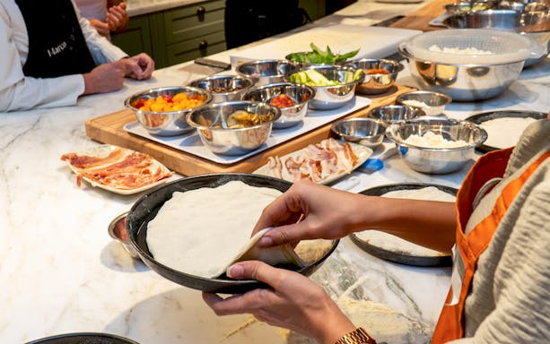 Preparing pizza dough with toppings in a Rome cooking class.
