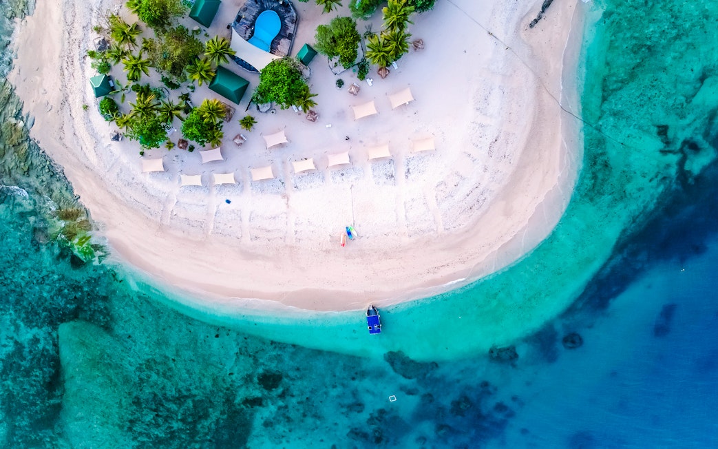 Aerial view of South Sea Island, Fiji with beach, palm trees, and turquoise waters.