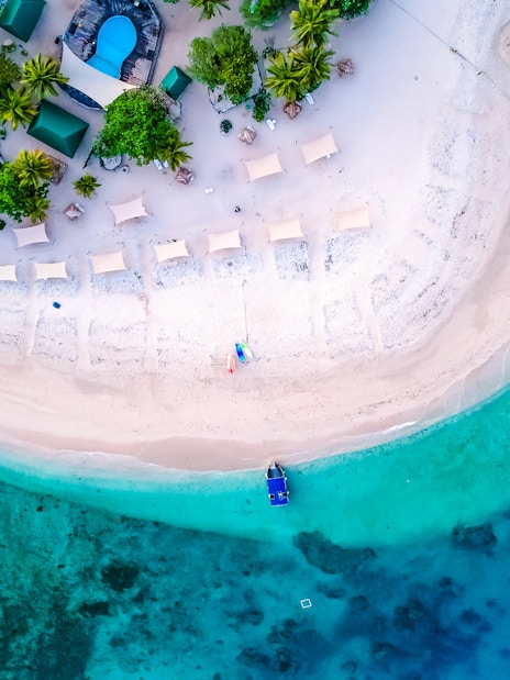 Aerial view of South Sea Island, Fiji with beach, palm trees, and turquoise waters.