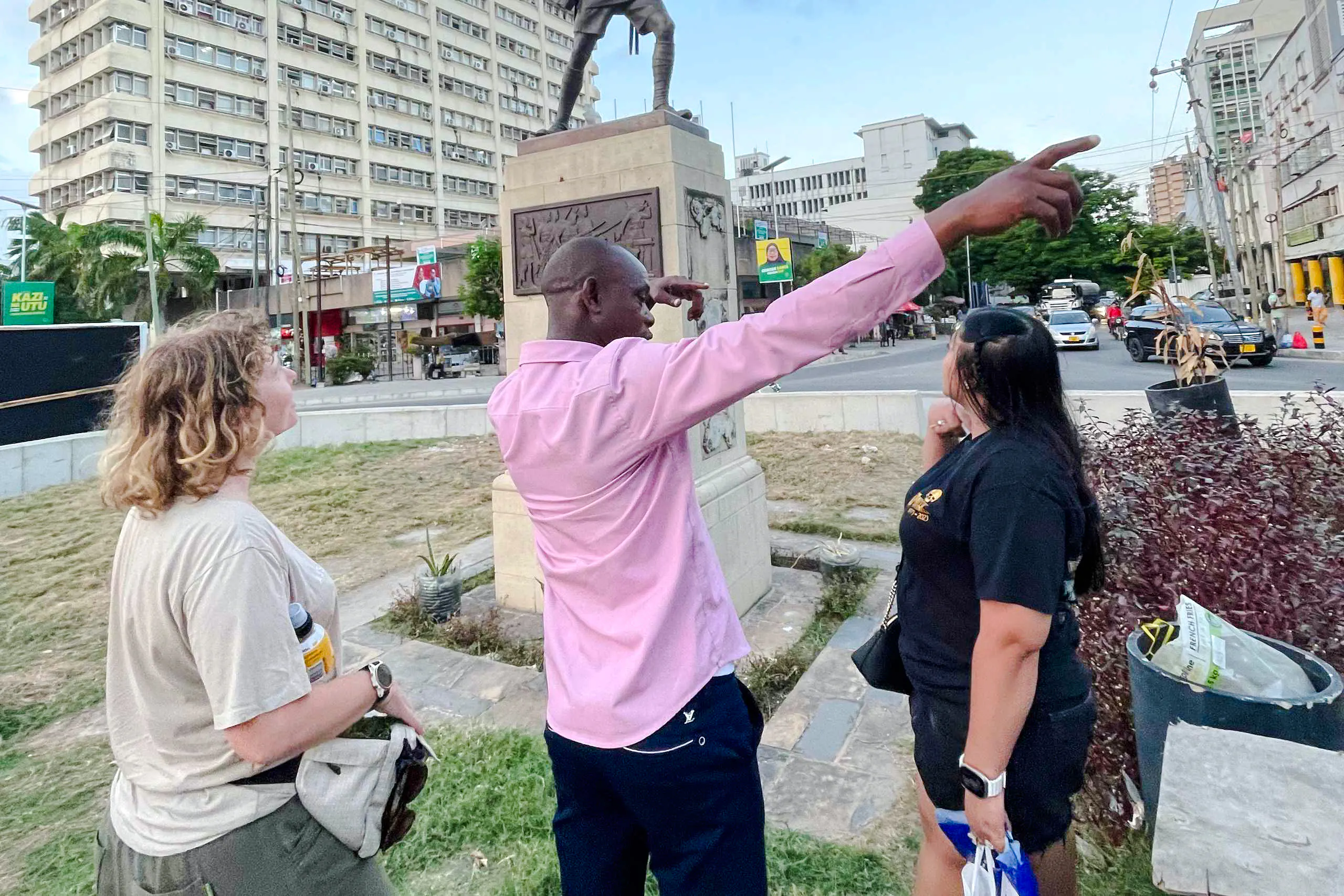 Tour guide pointing out historical landmarks in Dar es Salaam's Old Town during a walking tour.