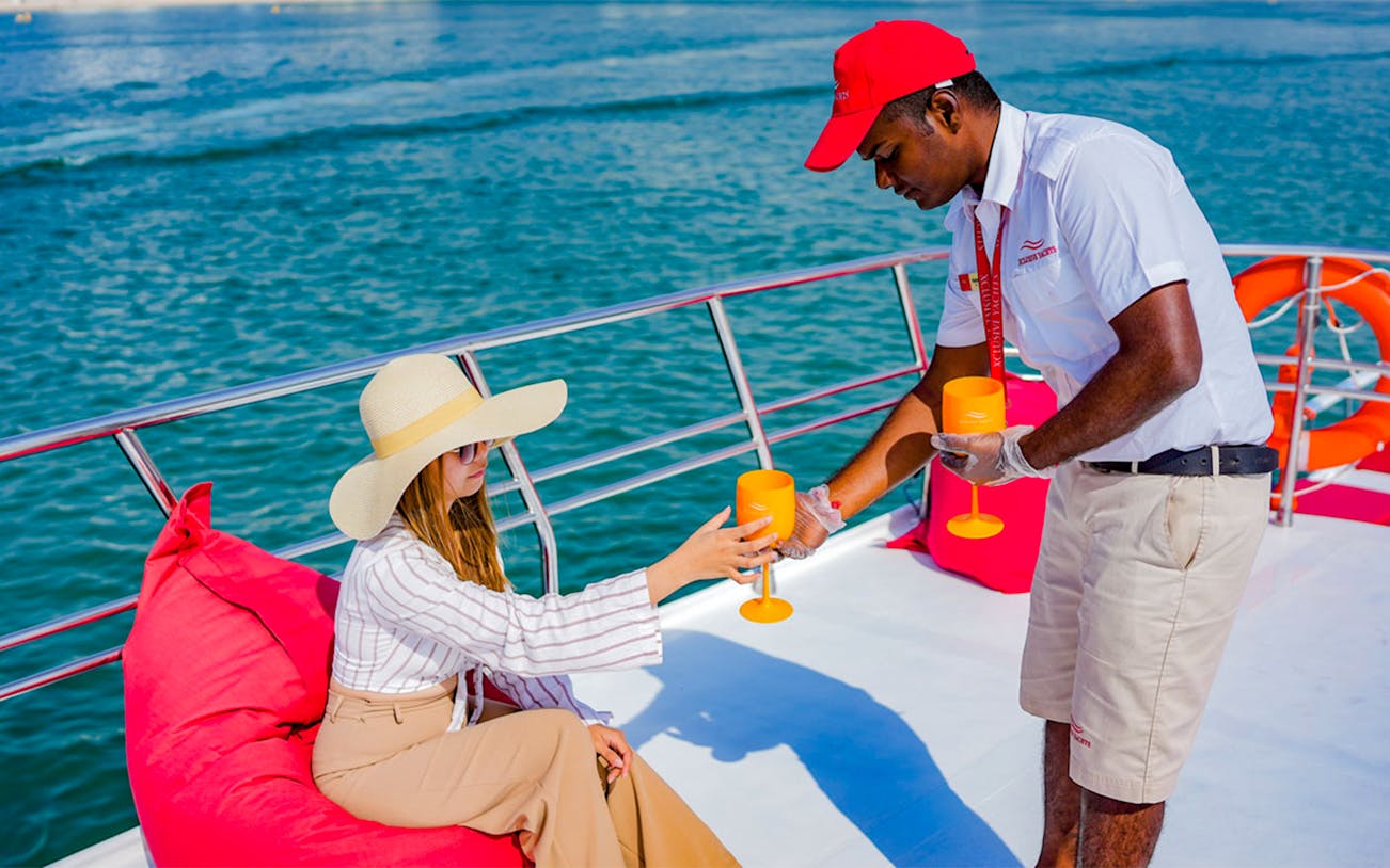 Person receiving a drink on a yacht during Dubai Marina sailing tour.