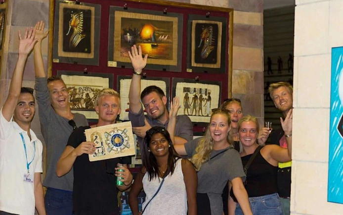 Group of tourists enjoying a shopping trip with a private guide in Hurghada, holding Egyptian artwork.