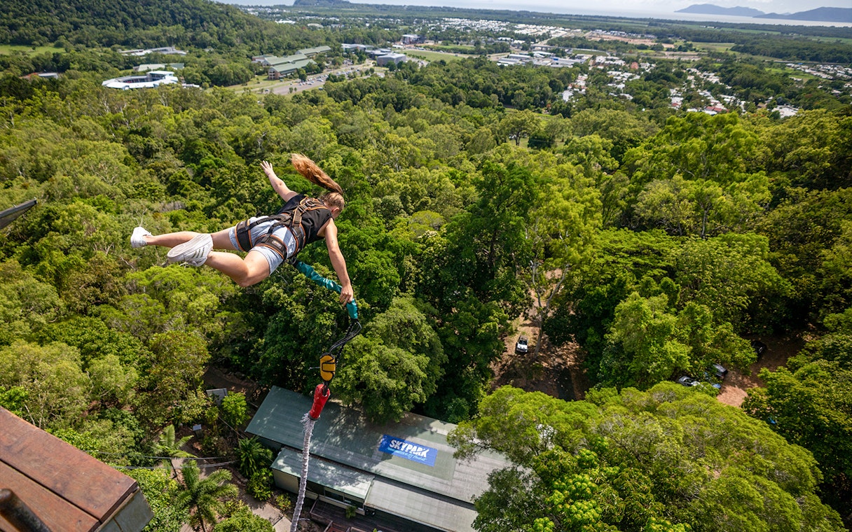Person bungy jumping over lush forest in Cairns, Australia.