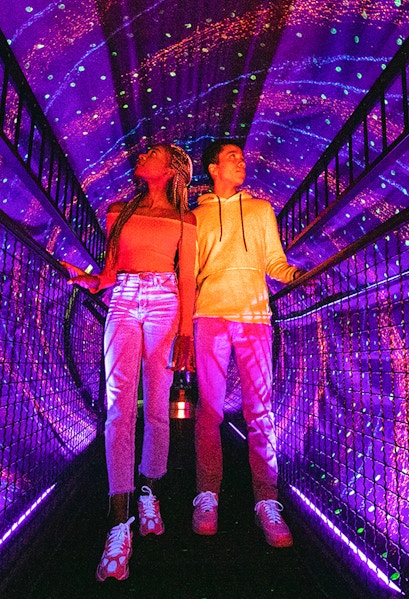 Visitors exploring a colorful light tunnel at Illuseum Berlin.