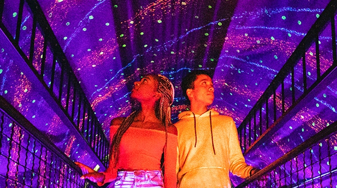 Visitors exploring a colorful light tunnel at Illuseum Berlin.