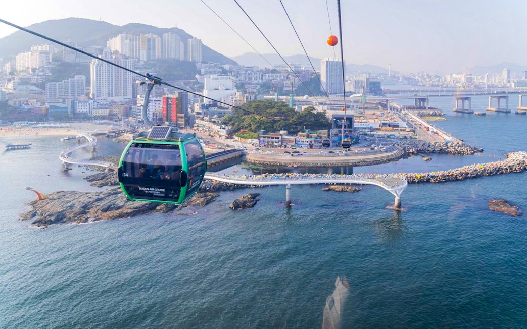 Cable car over Songdo Beach in Busan with cityscape and ocean view.