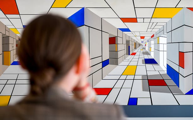 Visitor observing geometric art at Illusion Art Museum in Prague.