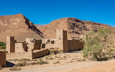 Traditional Kasbah in Ziz Valley, Morocco with desert landscape and mountains.