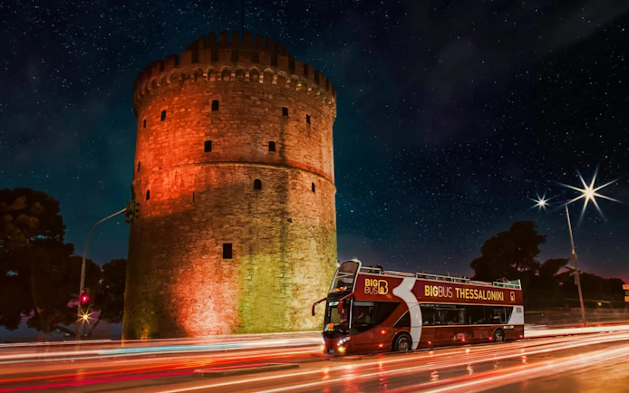 Big Bus passing the White Tower in Thessaloniki, Greece at night.