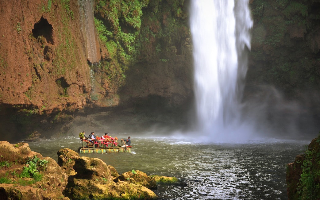 Boat near Ouzoud waterfall in Morocco with tourists enjoying the view.