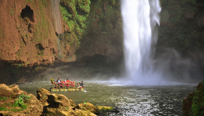 Boat near Ouzoud waterfall in Morocco with tourists enjoying the view.