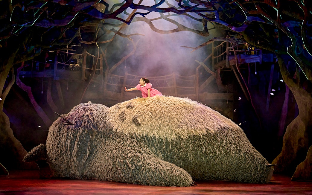 Child on Totoro's back in a forest setting during My Neighbour Totoro stage production.