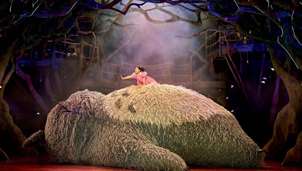 Child on Totoro's back in a forest setting during My Neighbour Totoro stage production.