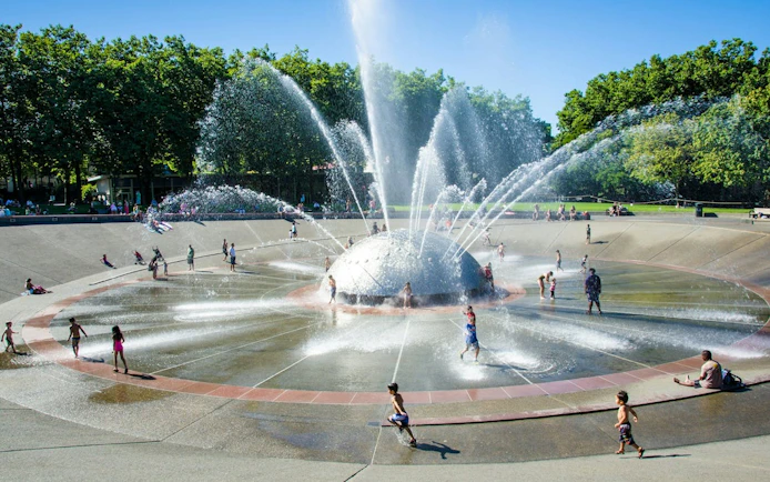 Children playing at the International Fountain in Seattle Center on a sunny day.