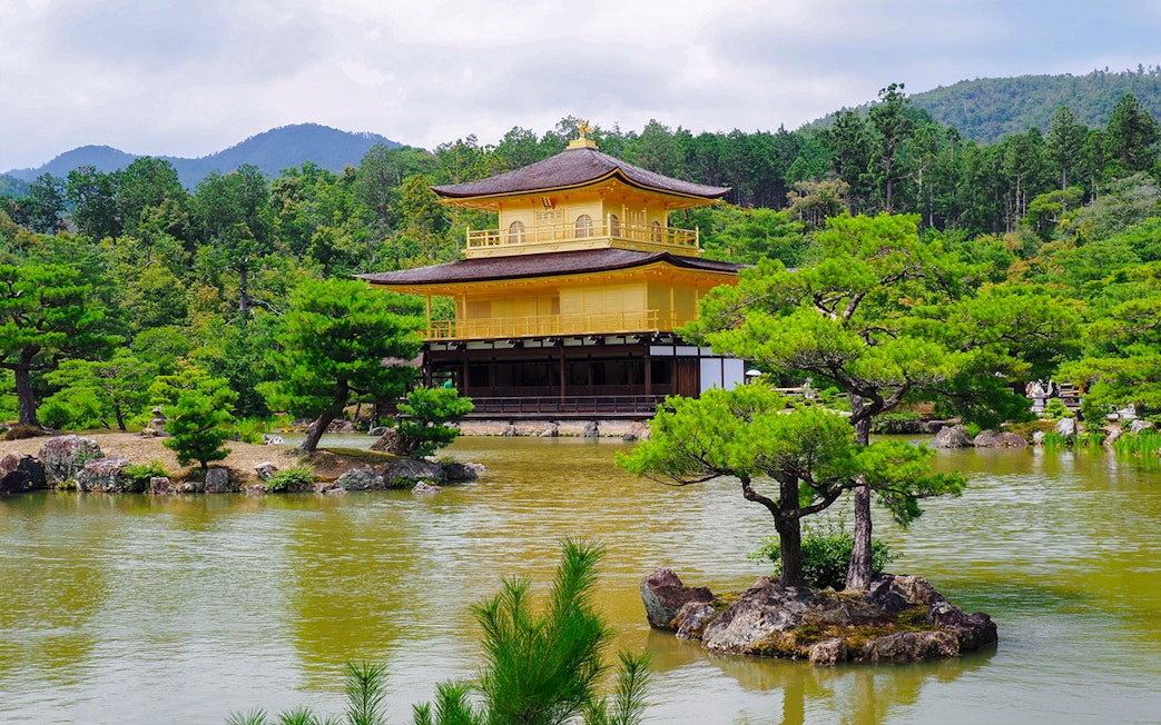 Kinkaku-ji temple in Kyoto surrounded by lush greenery and a reflective pond.