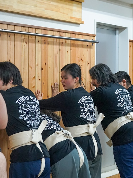 Participants learning sumo wrestling techniques in Tokyo dojo.