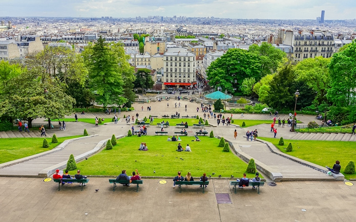 Visitors relaxing on benches in Montmartre with a view of Paris, near Sacré Coeur.