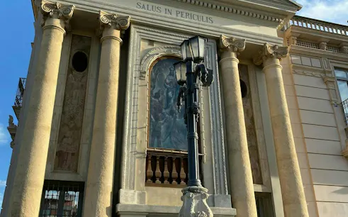 Facade of a historic building with columns and a mural in Murcia, part of the self-guided city exploration game.