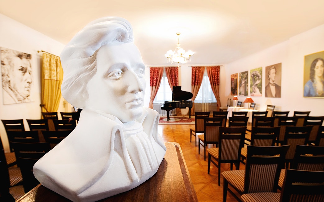 Bust of Chopin in concert room with grand piano and seating for Evening Chopin Piano Concert.