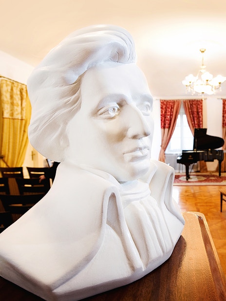 Bust of Chopin in concert room with grand piano and seating for Evening Chopin Piano Concert.