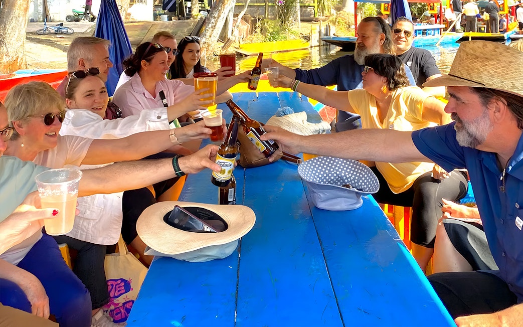 Guests toasting with drinks on a Trajinera party boat in Xochimilco.