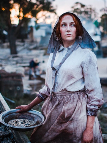 Woman in period costume panning for gold at Sovereign Hill, Australia.