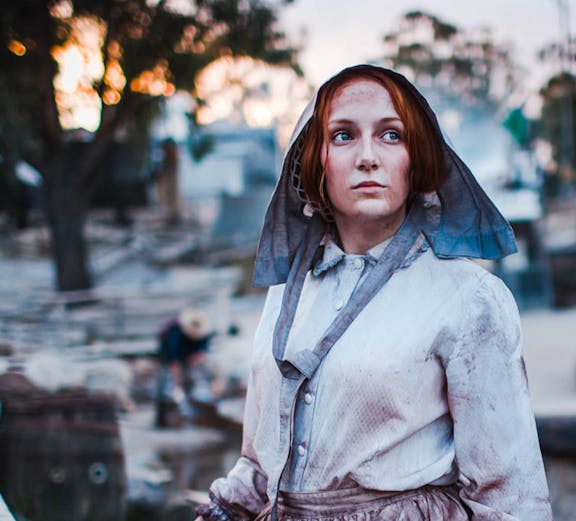 Woman in period costume panning for gold at Sovereign Hill, Australia.