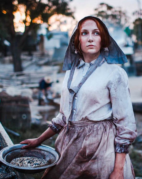 Woman in period costume panning for gold at Sovereign Hill, Australia.