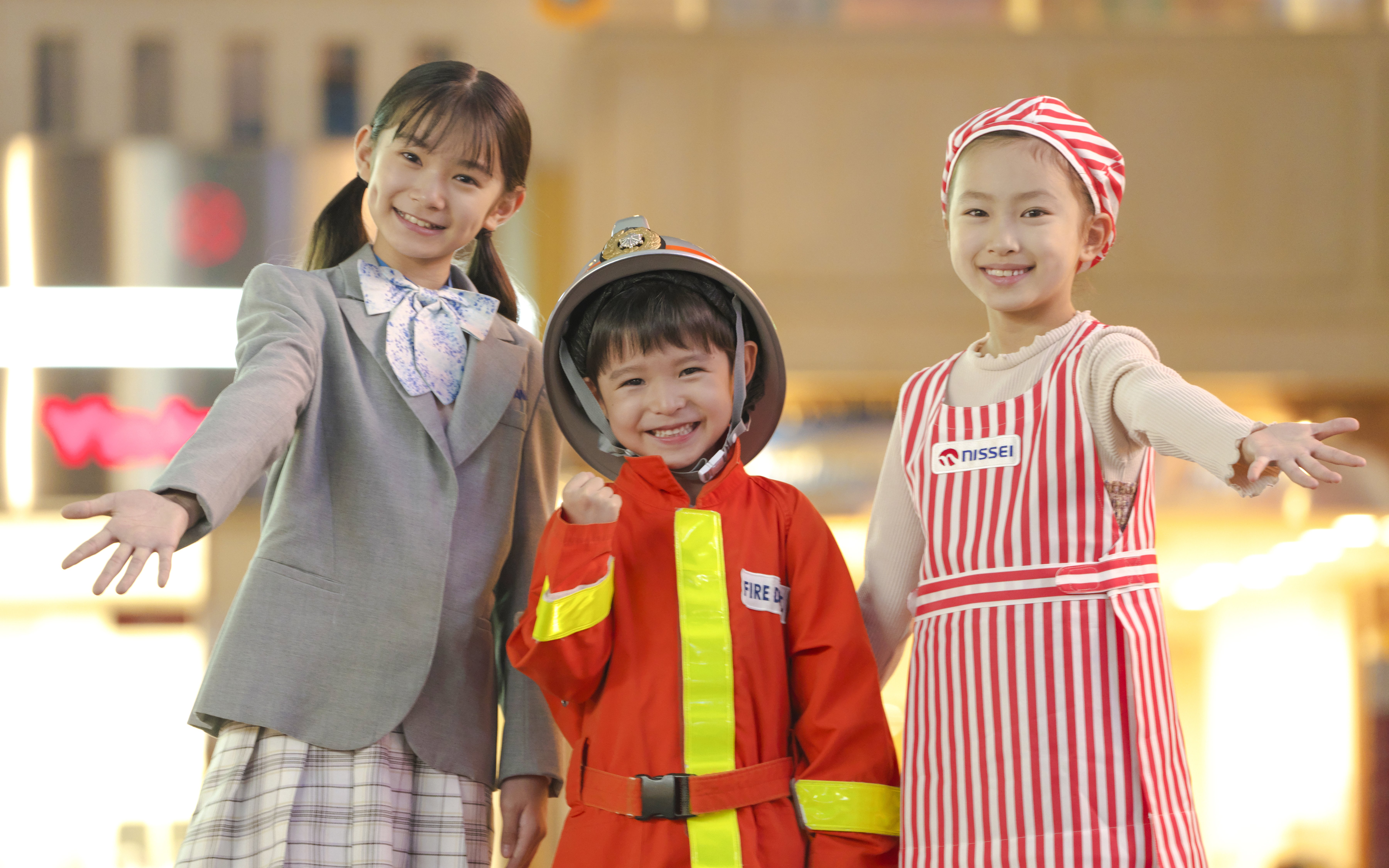 Kids in costumes at KidZania Tokyo, including a firefighter and a chef.