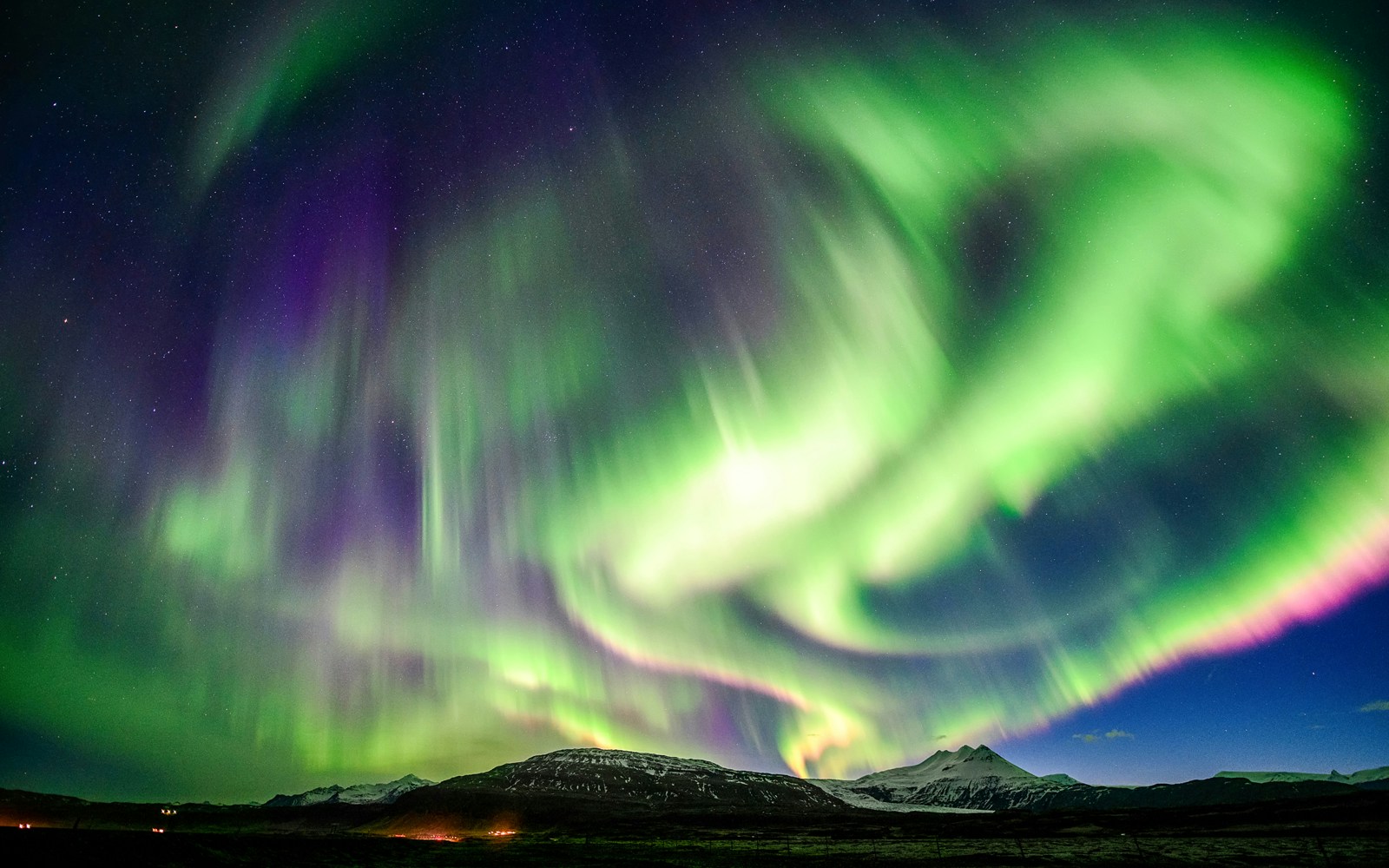 Aurora borealis over snowy mountain at night.