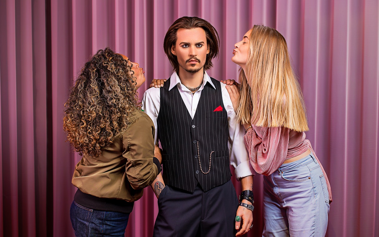 Wax figure at Madame Tussauds Amsterdam with visitors posing.