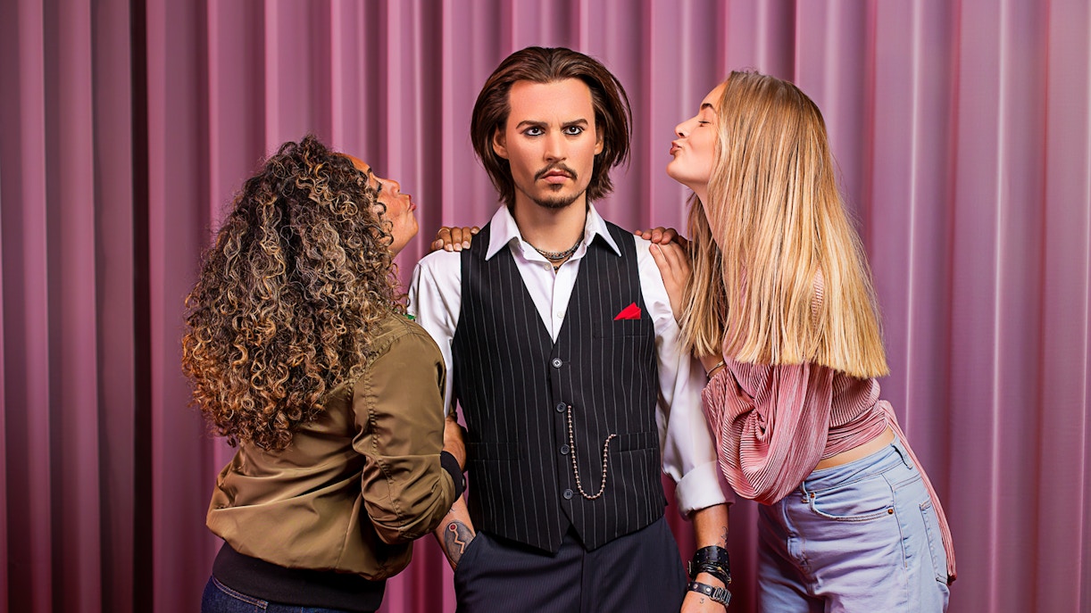 Wax figure at Madame Tussauds Amsterdam with visitors posing.