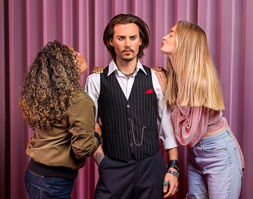 Wax figure at Madame Tussauds Amsterdam with visitors posing.