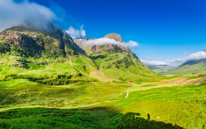 Glencoe Scotland mountain landscape with green valleys and cloudy peaks.