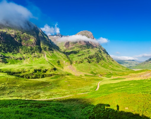 Glencoe Scotland mountain landscape with green valleys and cloudy peaks.