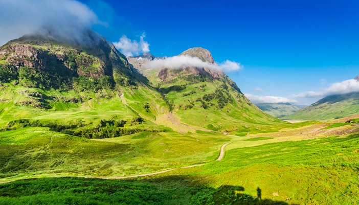 Glencoe Scotland mountain landscape with green valleys and cloudy peaks.