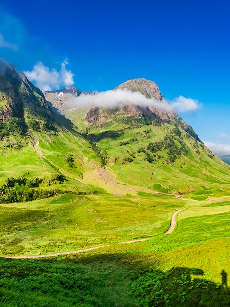 Glencoe Scotland mountain landscape with green valleys and cloudy peaks.