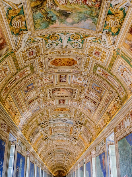 Vatican Museums' ornate hallway ceiling with detailed frescoes and maps.