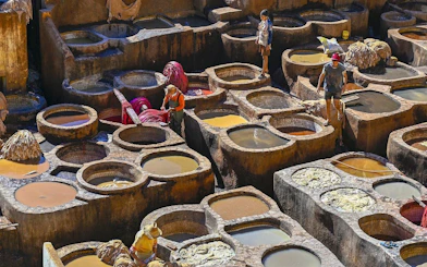 Tannery workers at Chouara Tannery in Fes Old Medina, Morocco, dyeing leather in stone vats.