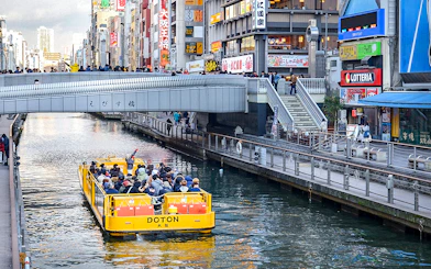 Tombori River Cruise boat passing under Ebisu Bridge in Osaka, Japan.
