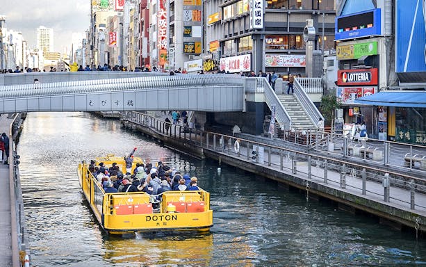 Tombori River Cruise boat passing under Ebisu Bridge in Osaka, Japan.