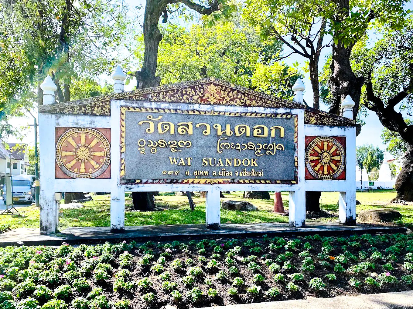 Wat Suan Dok entrance sign surrounded by trees in Chiang Mai.