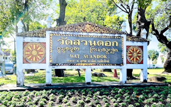 Wat Suan Dok entrance sign surrounded by trees in Chiang Mai.