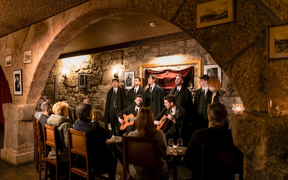 Fado musicians performing at Fado Maior with audience seated in a cozy stone-walled venue.