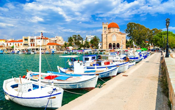 Traditional fishing boats docked near St. Nicholas Church in Aegina, Greece.